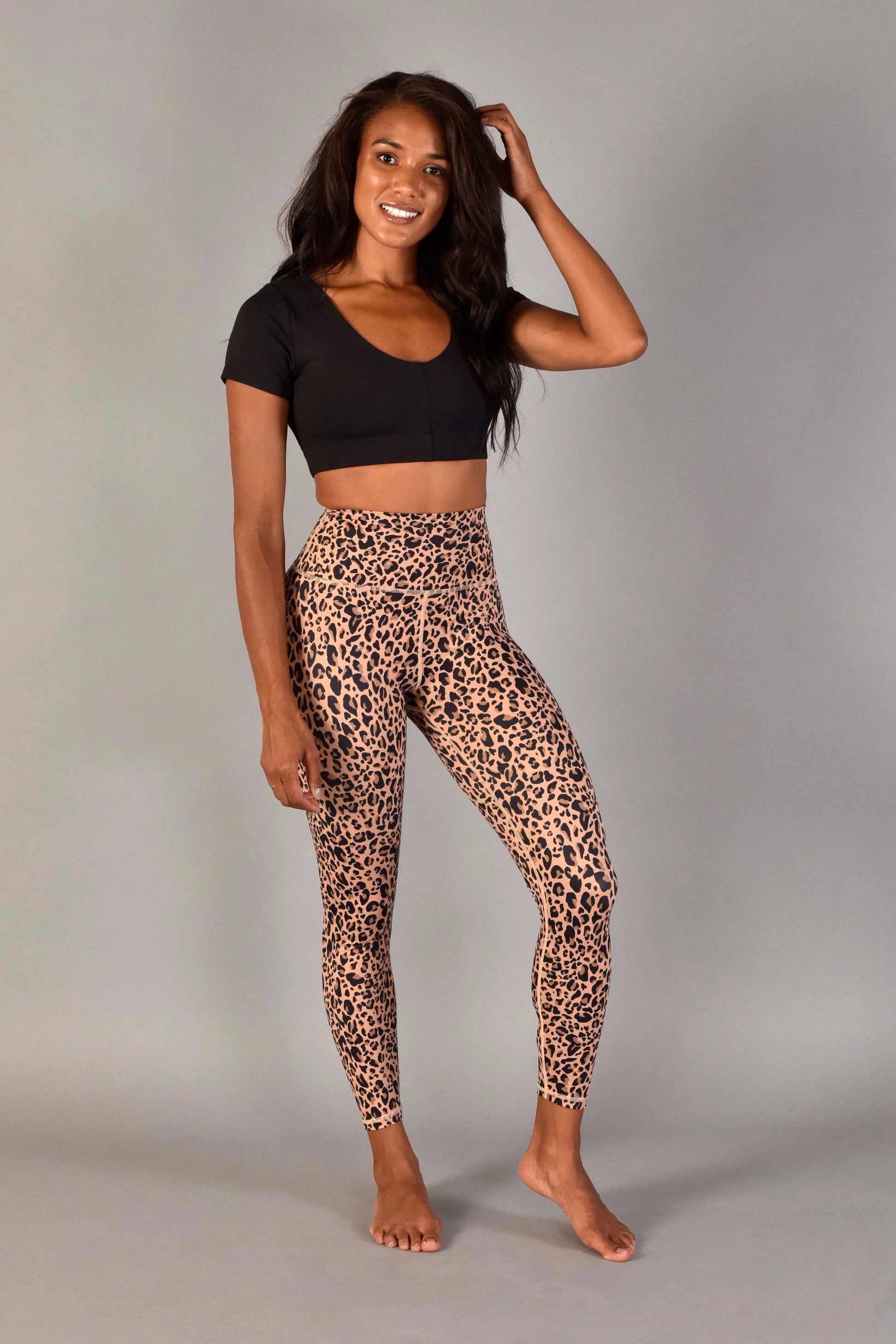 WEAR LOVE MORE Sustainable and Supportive Sports Bras.  Audrey Reversible Sports Top in Recycled Matte Black Core Compression.  V-neck Front View.  Paired with Nude Leopard Legging.