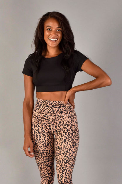 WEAR LOVE MORE Sustainable and Supportive Sports Bras. Audrey Reversible Sports Top in Recylcled Matte Black Core Compression.  Boatneck Front View.  Paired with Nude Leopard Legging. Shown on Model wearing Size Small who is 32D.